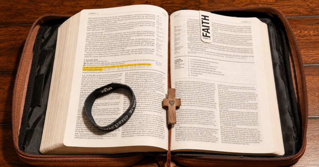 Iron Sharpens Iron Scripture bracelet resting on an open Bible, highlighted at James 1:22, next to a wooden cross